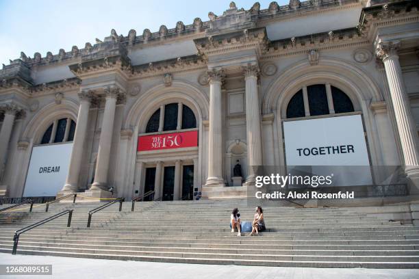 People weairng masks sit on the stairs at The Metropolitan Museum of Art where Yoko Ono's new art installation, Dream Together, is displayed on the...