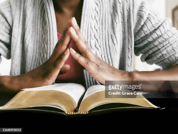woman prays while reading scripture - black woman praying stock pictures, royalty-free photos & images