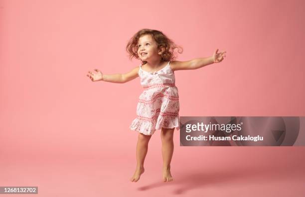 ragazza carina con salto a piedi nudi su sfondo rosa. - vestito da donna foto e immagini stock