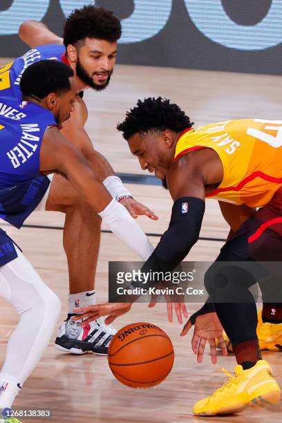 Monte Morris and Jamal Murray of the Denver Nuggets go after a loose ball against Donovan Mitchell of the Utah Jazz during the second quarter in Game...