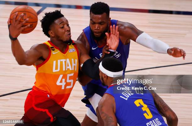 Donovan Mitchell of the Utah Jazz drives against Paul Millsap and Torrey Craig of the Denver Nuggets during the fourth quarter in Game Four of the...