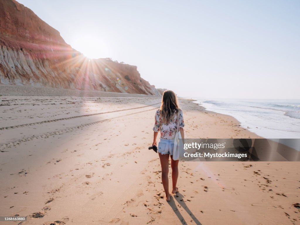 Junge Frau zu Fuß am portugiesischen Strand bei Sonnenaufgang