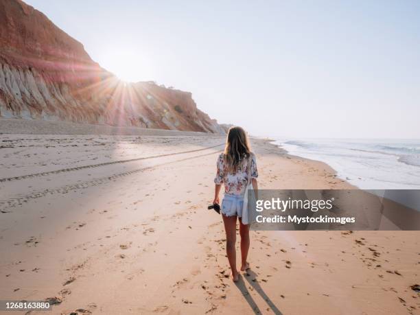 jonge vrouw die op portugees strand bij zonsopgang loopt - albufeira beach stockfoto's en -beelden