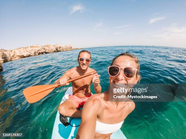 couple take selfie on inflatable sup in portugal - portugal beach stock pictures, royalty-free photos & images