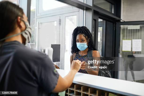 young african woman with face mask checking at gym and taking key - gym reopening stock pictures, royalty-free photos & images