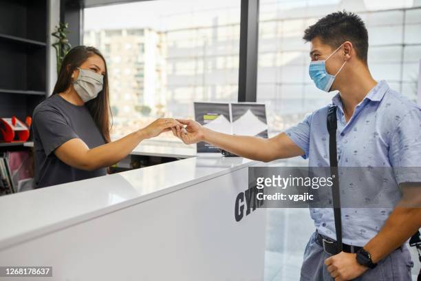 young man with face mask checking at gym and taking key - entering gym stock pictures, royalty-free photos & images