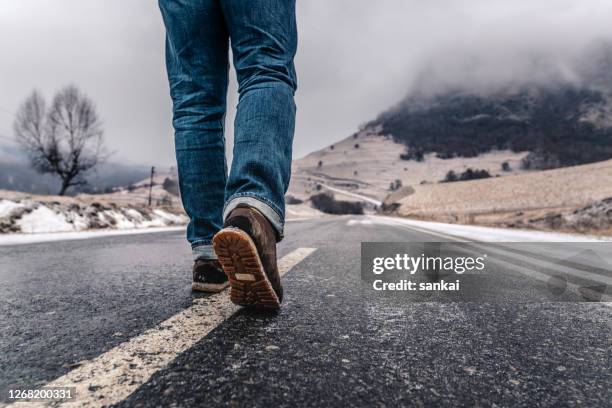 de mens loopt alleen op een lege weg in bergen. - destiny stockfoto's en -beelden