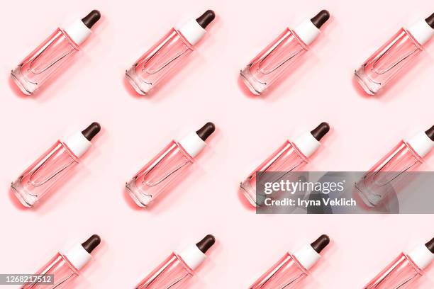 pattern made of glass bottle of oil with a pipette or face serum on a pastel pink background. - serum sample stock pictures, royalty-free photos & images