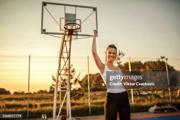 young female with a basketball in an outdoor court - basketball court stock pictures, royalty-free photos & images