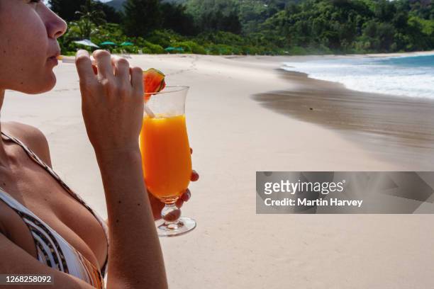cropped view of a beautiful woman drinking a cocktail on the beach - creole ethnicity stockfoto's en -beelden