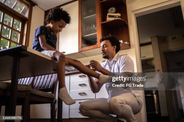 father taking care of son with hurt knee at home - applying bandage stock pictures, royalty-free photos & images