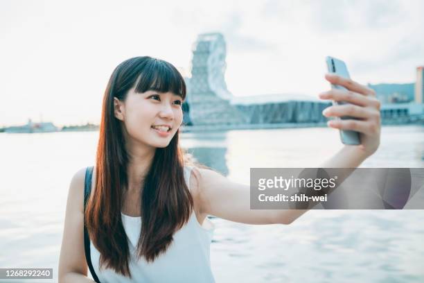 アジアの女性の笑顔は自分撮りを取る - 自分撮り ストックフォトと画像