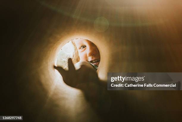 child reaching into a small hole with an outstretched hand - entrometido fotografías e imágenes de stock