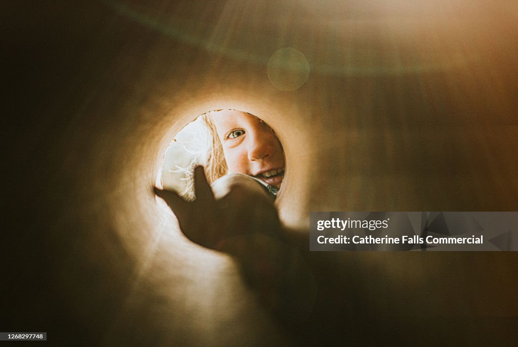 Child reaching into a small hole with an outstretched hand