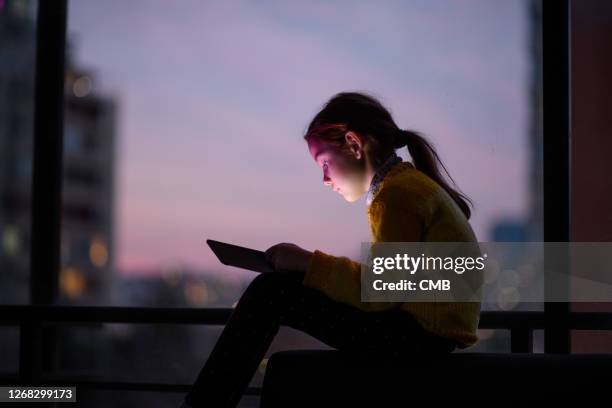 girl concentrated on playing with stablet at sunset - screen time stock pictures, royalty-free photos & images