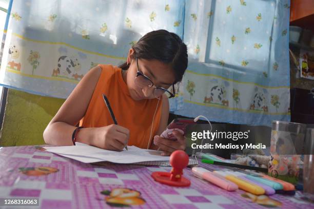 Girl takes notes as she follows online classes on a smartphone during the start of the school year from home on August 24, 2020 in Nezahualcoytl,...