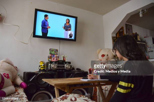 Student takes notes as she follows classes on the television during the start of the school year from home on August 24, 2020 in Nezahualcoytl,...