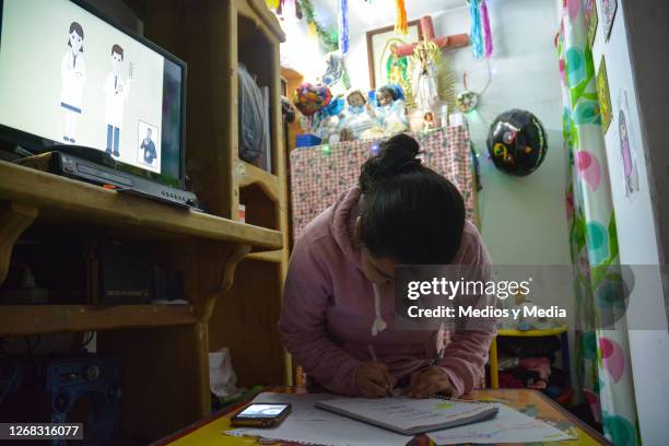 Student takes notes as she follows clases on the TV and smartphone during the start of the school year from home on August 24, 2020 in Nezahualcoytl,...