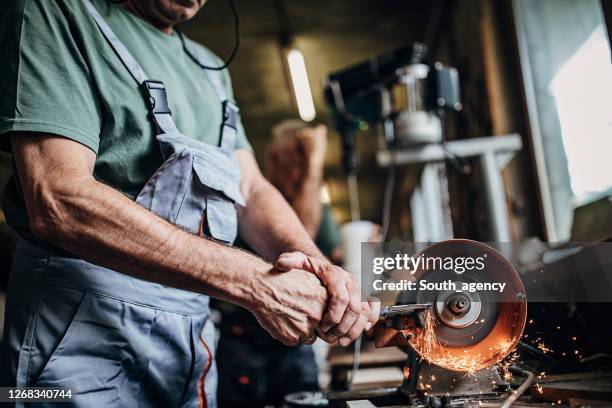 hogere mens die in werkplaats werkt - scherp stockfoto's en -beelden