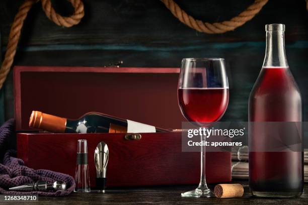 low key image of red wine bottle and cup in a rustic nautical environment bar - low alcohol drink stock pictures, royalty-free photos & images