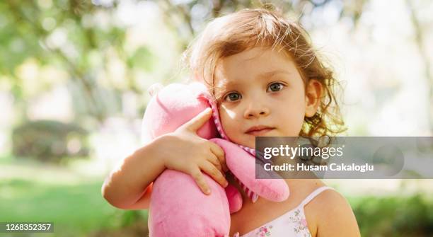 cute little girl playing with her doll near the tree in a park. - one baby girl only stock pictures, royalty-free photos & images