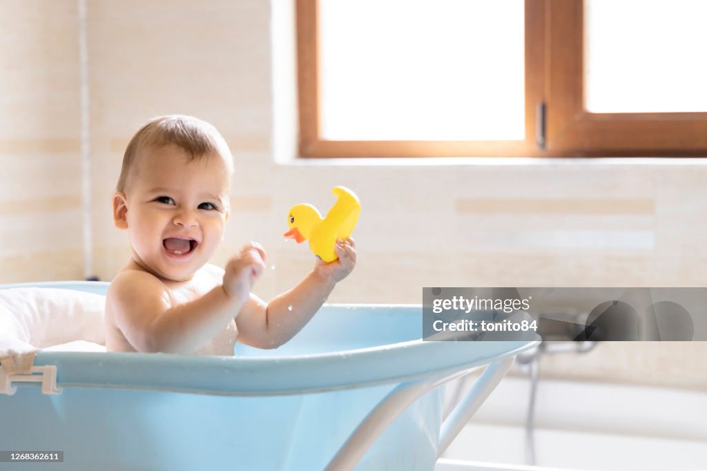 Un bebé lindo se está bañando en la bañera. Un bebé que salpica agua mientras se baña