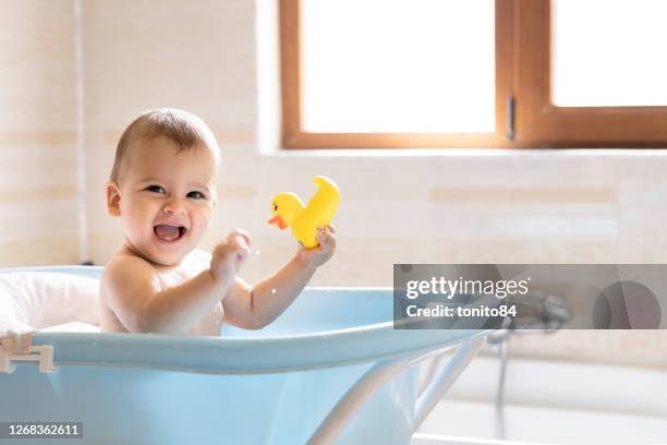 a cute baby is bathing in the tub. a baby who splashes water while bathing - bathtub stock pictures, royalty-free photos & images