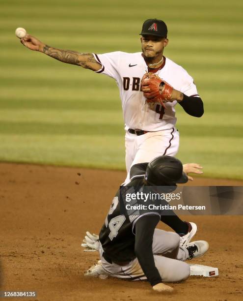 Infielder Ketel Marte of the Arizona Diamondbacks throws over Ryan McMahon of the Colorado Rockies to complete a double play during the eighth inning...