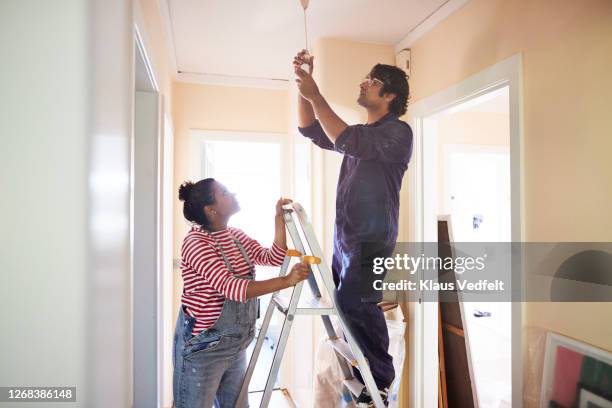 couple changing light bulb in corridor - changing your life stockfoto's en -beelden