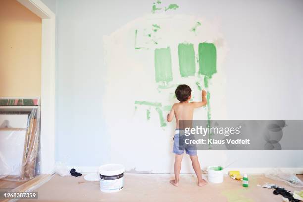 boy painting wall during home renovation - boy barefoot rear view stockfoto's en -beelden