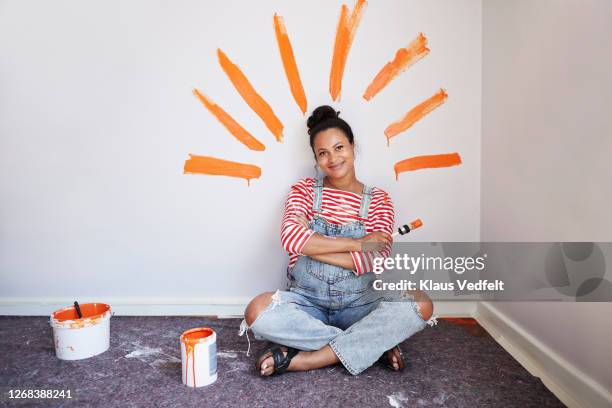 woman with brush strokes on wall renovating home - orange couleur photos et images de collection