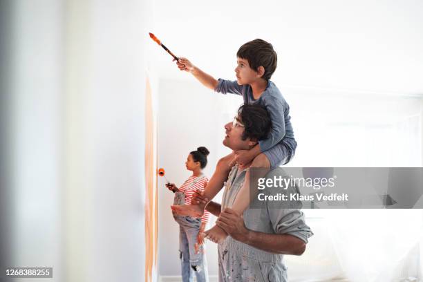 family painting wall during home renovation - two parents stock pictures, royalty-free photos & images
