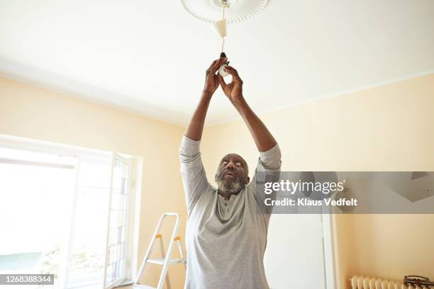 man changing light bulb while renovating home - hanging lamp stock pictures, royalty-free photos & images