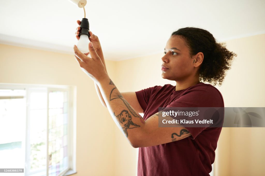 Woman changing light bulb in living room