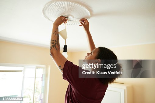 Woman connecting light bulb on ceiling at home Woman connecting light bulb on ceiling at home