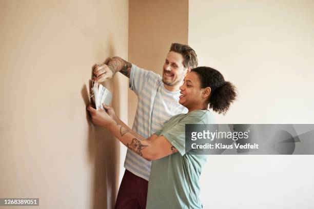 smiling couple choosing paint color for home - renovation home stock-fotos und bilder