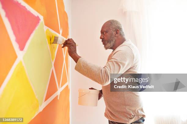 elderly man painting design on wall at home - black room photos et images de collection