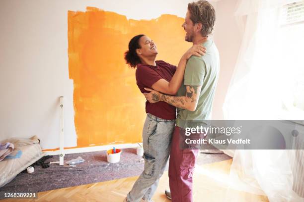 cheerful couple at home during renovation - fond orange fotografías e imágenes de stock