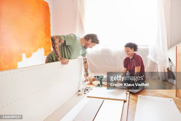 couple positioning planks during home renovation - renovatie begrippen stockfoto's en -beelden