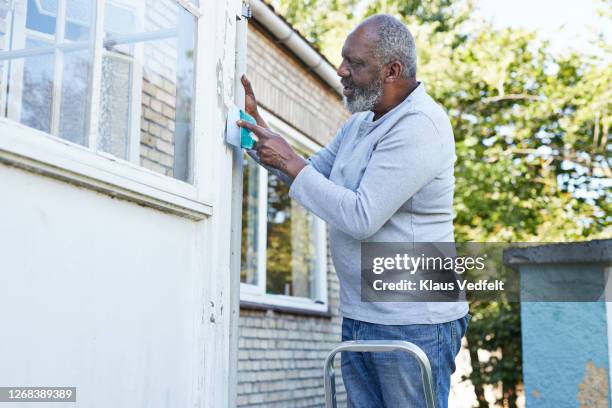 man scraping wall of house during renovation - cleaning walls stock pictures, royalty-free photos & images