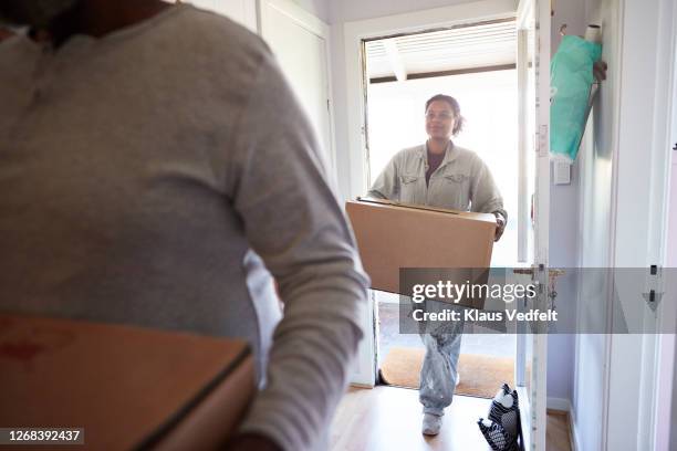 woman with cardboard box entering in new home - new arrival stock pictures, royalty-free photos & images