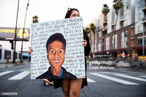 Person holds a sign at a candlelight vigil to demand justice for Elijah McClain on the one year anniversary of his death at The Laugh Factory on...