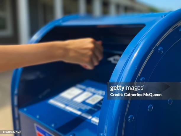 side profile view of mixed-race female mailing letter at traditional blue postal mailbox - postal 個照片及圖片檔