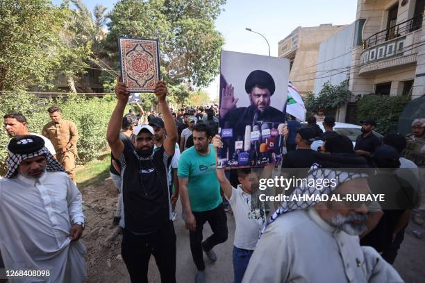 Supporter of Moqtada Sadr raises a picture of the Shiite Muslim leader, as another carries a Koran, during a demonstration outside the Swedish...