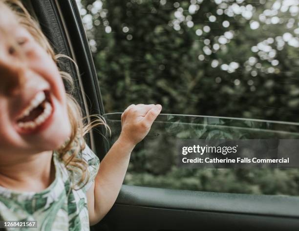 background image of a little girl laughing beside an open car window - road trip kids stock pictures, royalty-free photos & images