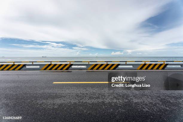 asphalt road by the sea - roadside photos et images de collection