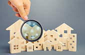 Real Estate Agent examines houses through a magnifying glass. Review of the real estate market, search for the best offers based on the criteria of price, location, area, infrastructure. Customer preferences.