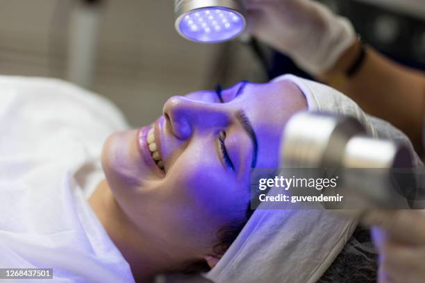 kvinna kosmetolog gör blue light therapy på framsidan av vackra unga kvinna - beauty laser bildbanksfoton och bilder