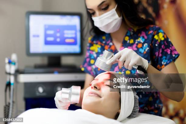 cosmetologist making infrared light therapy facial treatment - alternative therapy stock pictures, royalty-free photos & images