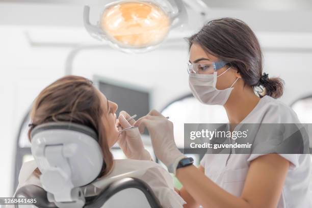 dentista donna che esamina la sua paziente in clinica dentale - igiene dentale foto e immagini stock